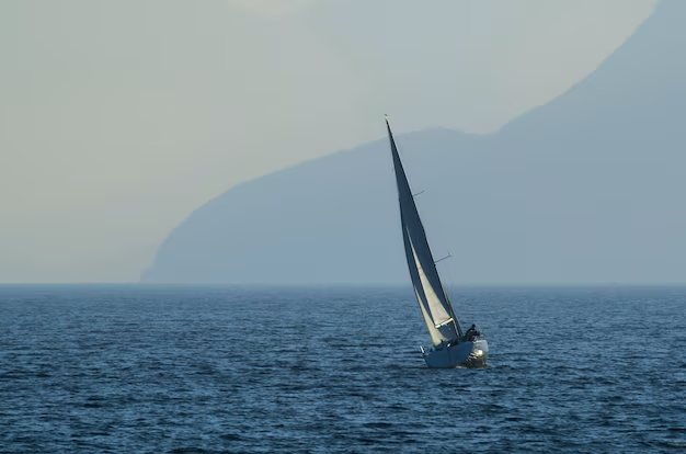 Sailboat on the open sea against the backdrop of mountains