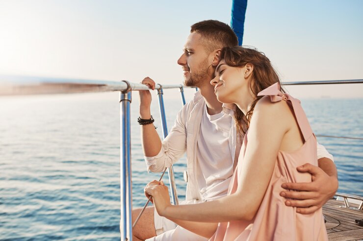 A man and a woman standing hugging on a yacht