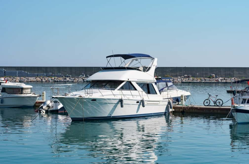 A white motor yacht moored in a calm marina with bicycles nearby