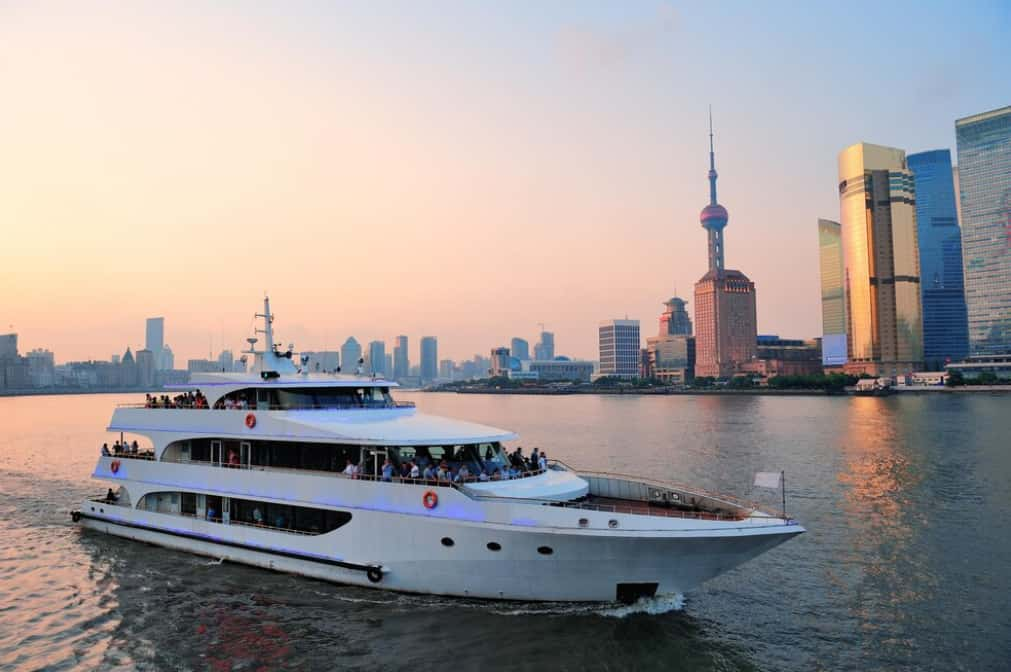 Large yacht cruising by a city skyline at sunset