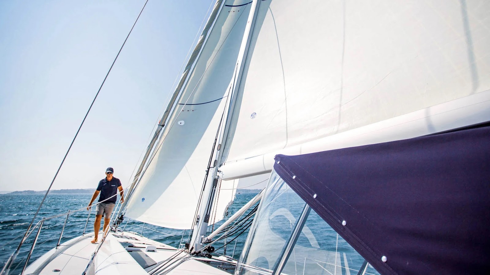 A man walks on the deck next to the sails